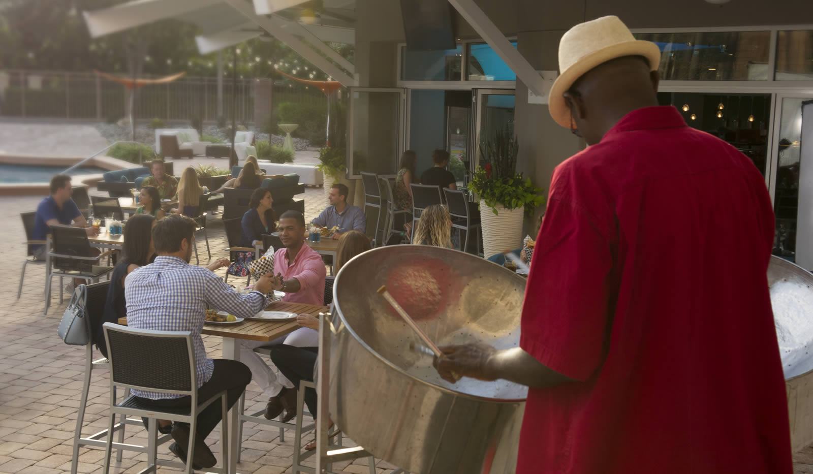 Gentleman playing steel drums at a poolside restaurant.